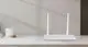Weißer Router von hoymiles mit zwei Antennen auf einem schlichten Tisch, neben einer Tasse auf einem Holzuntersetzer und einige Bücher im Hintergrund.
